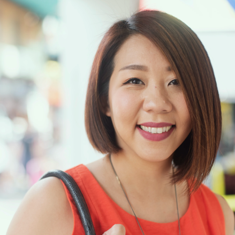 Smiling woman with shoulder-length hair in a red top indoors.