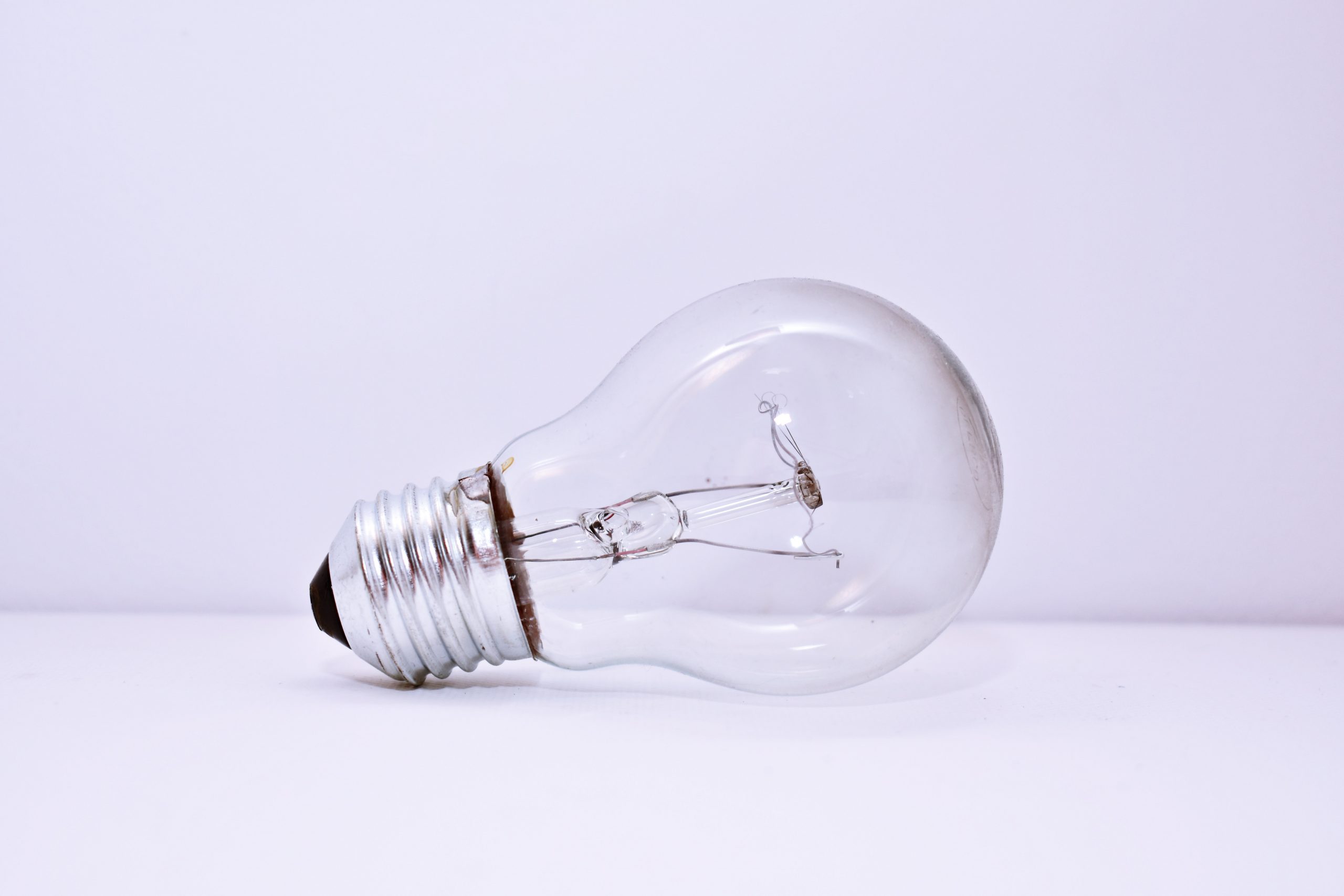 A clear incandescent light bulb lying on its side against a white background.