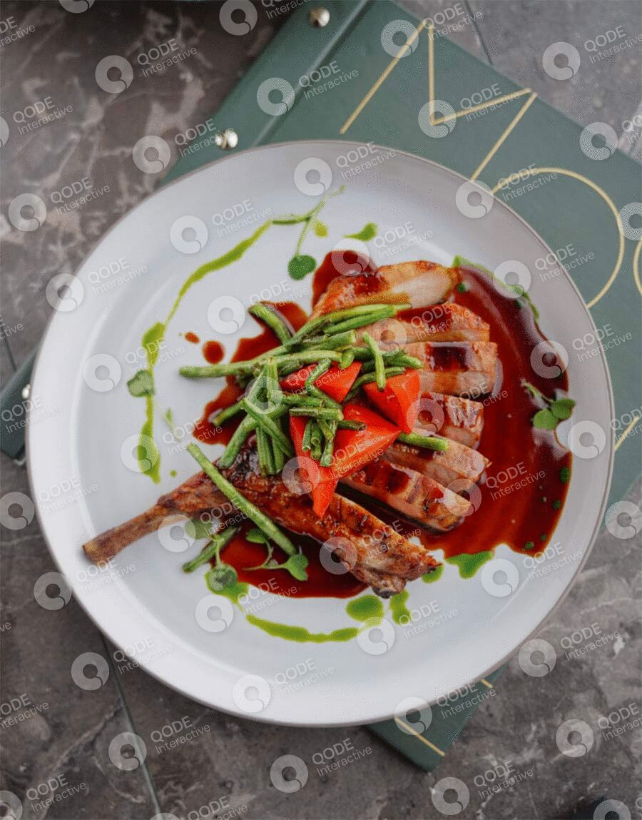 A gourmet lamb chop dish garnished with greens and sauces.