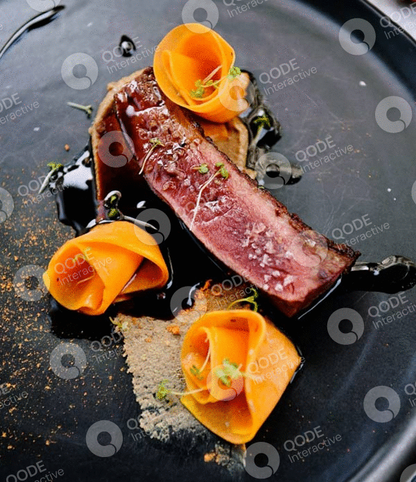 Gourmet steak with orange edible flowers on a black plate.