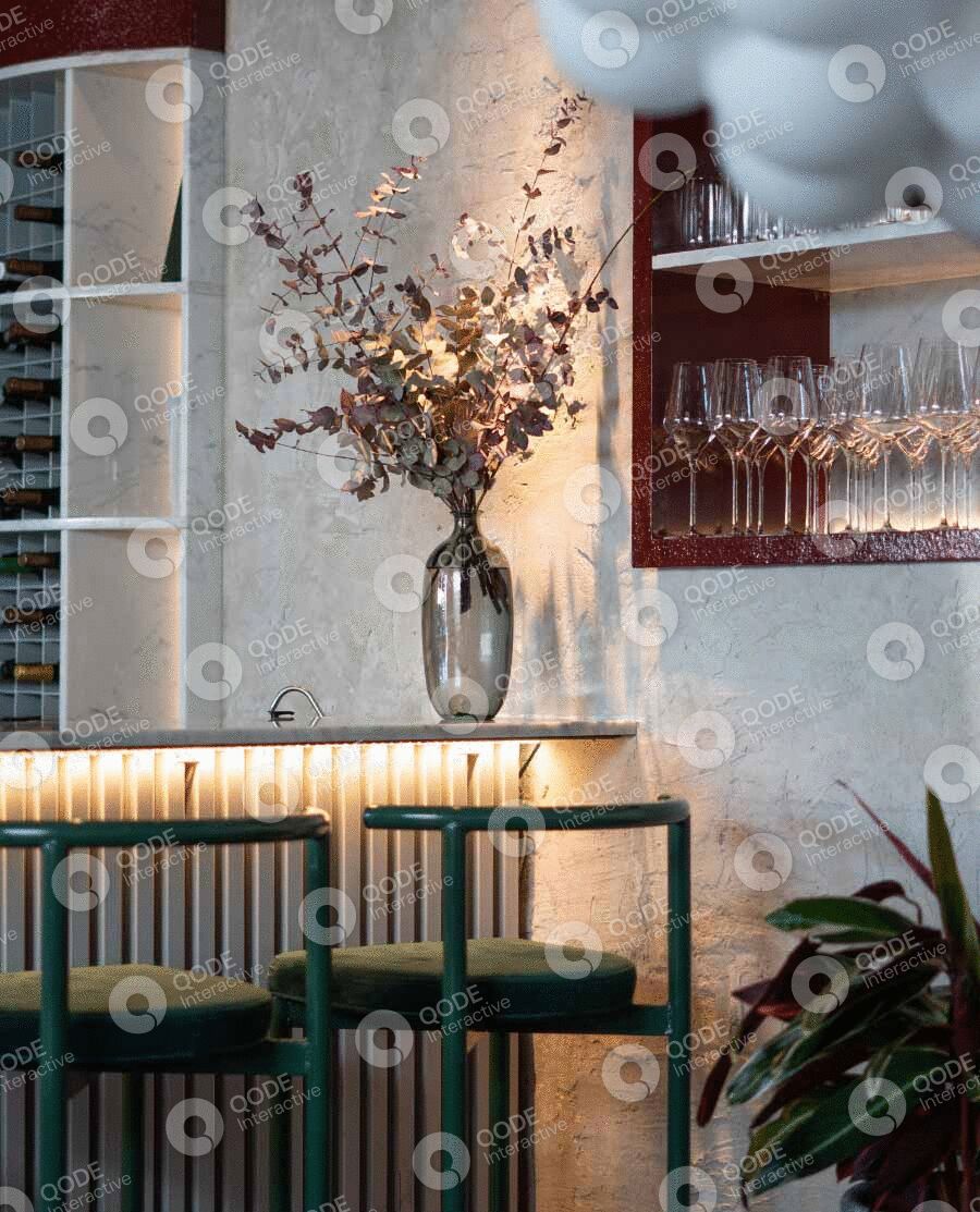 Elegant dining area with green chairs and floral centerpiece in a glass vase.