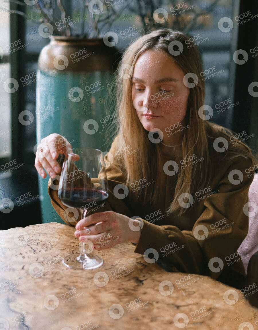 Woman enjoying a glass of red wine at a cozy bar.