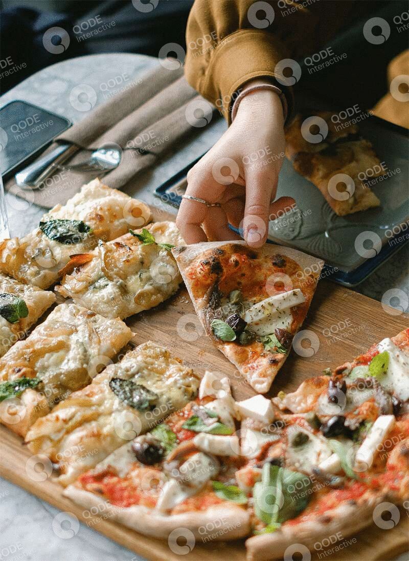 Hand grabbing a slice of vegetable pizza from a box.