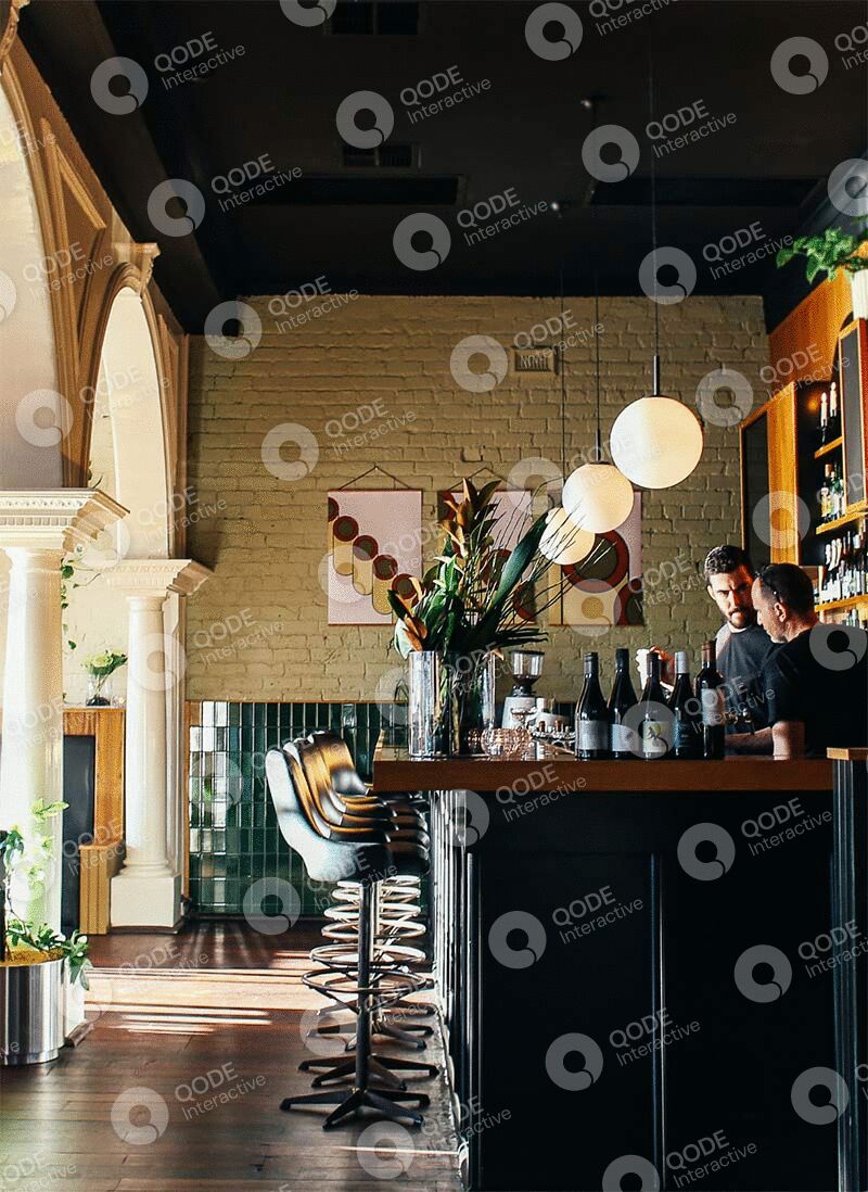 Cozy bar interior with wooden stools and warm lighting.