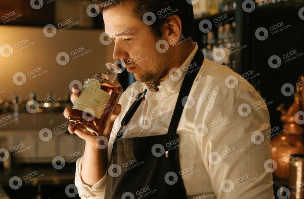 Bartender smelling a drink in a cozy bar setting.