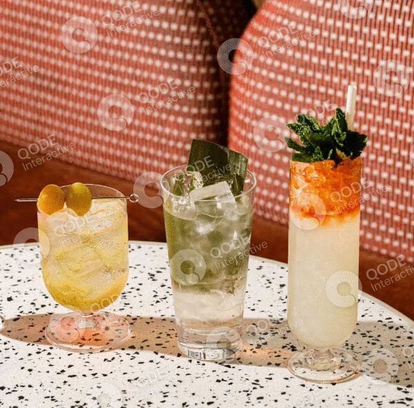 Three stylish cocktails on a lace tablecloth with patterned chairs in the background.