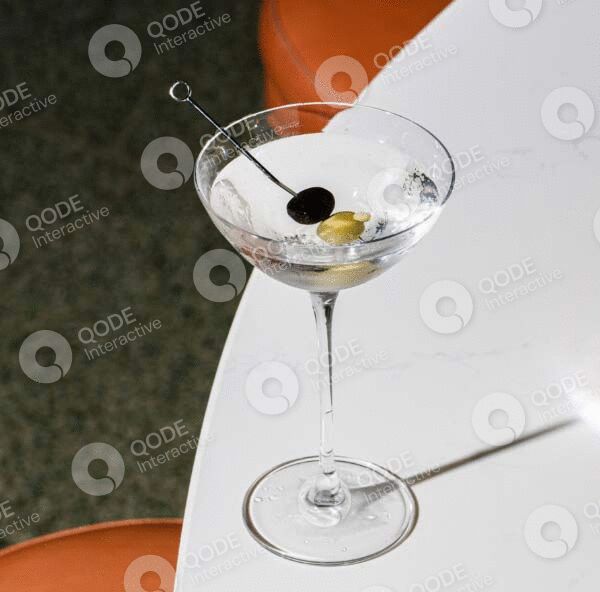 Elegant martini glass with two olives on a white table.
