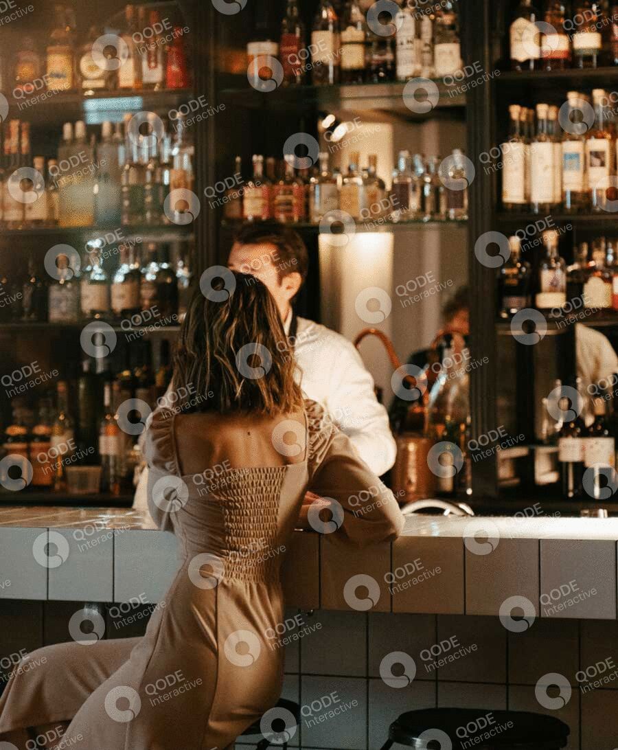 A woman talking to a bartender in a cozy bar.