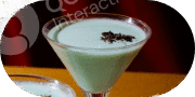 A creamy green cocktail garnished with chocolate shavings in a martini glass.