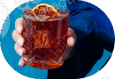 Hand holding a glass of iced beverage with lemon peel.
