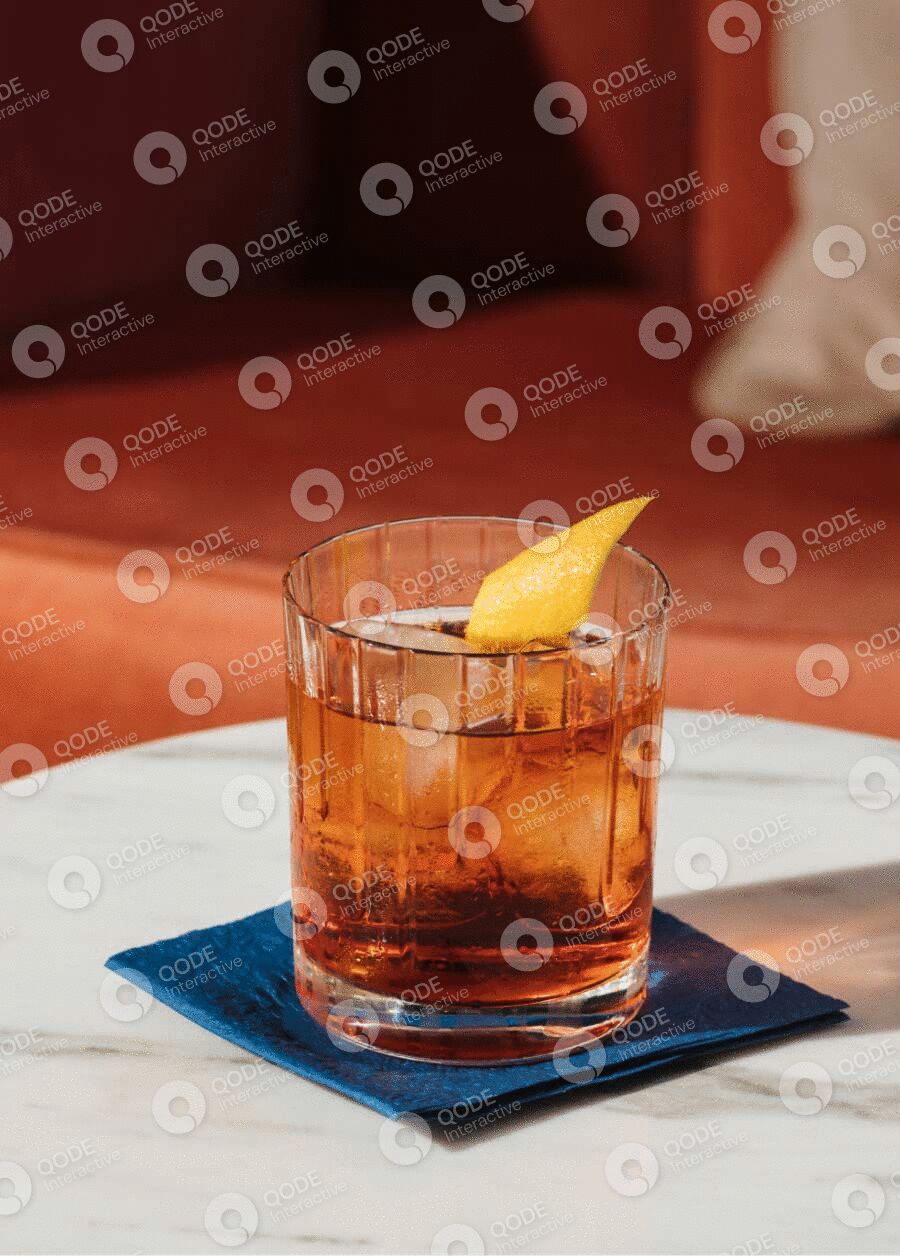 A stylish cocktail with an orange twist on a blue coaster.