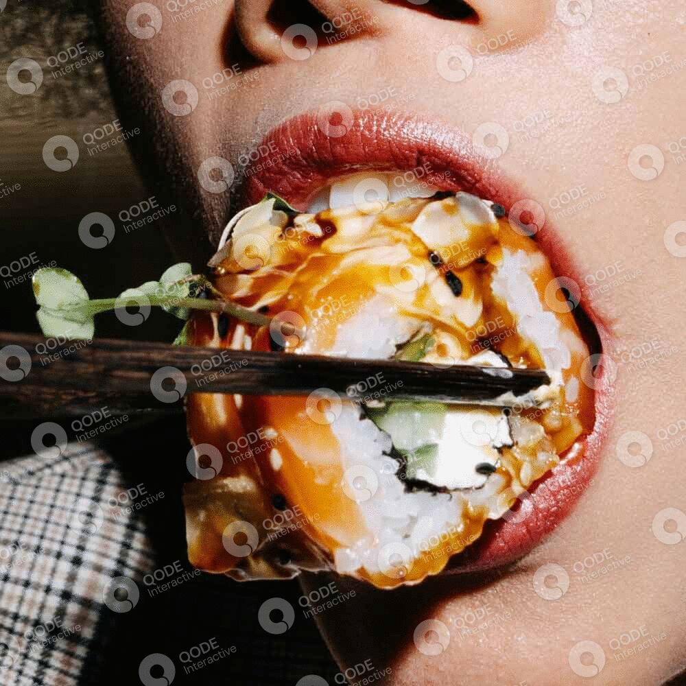 Person eating sushi with chopsticks close-up.