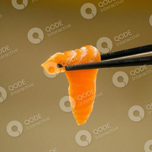 A piece of salmon sushi held by black chopsticks.