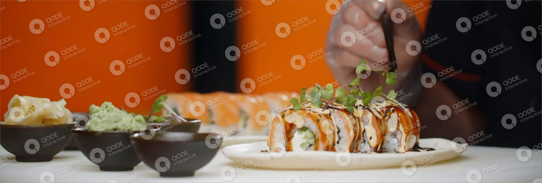 Close-up of sushi rolls with sauce and garnish on a white plate.