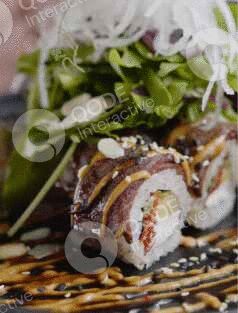 Close-up of sushi rolls garnished with sauce and greens.