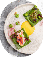 Gourmet dish with vibrant vegetables and a yellow sauce on a textured plate.