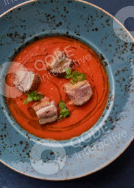 Gourmet dish with seared meat and green garnish on a vibrant orange sauce.