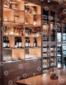 Elegant wine storage with bottles and glasses on wooden shelves.