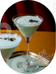 Two green mint cocktails garnished with cloves on a yellow table.