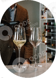 Two wine glasses on a table with a person in the background.