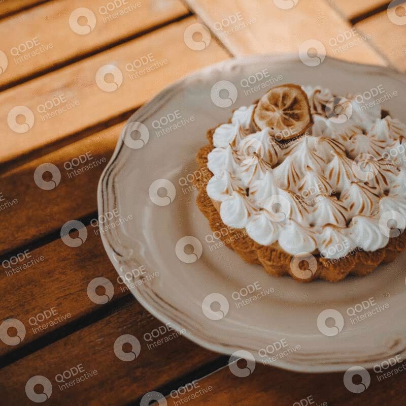A cream-topped tart on a ceramic plate on a wooden table.