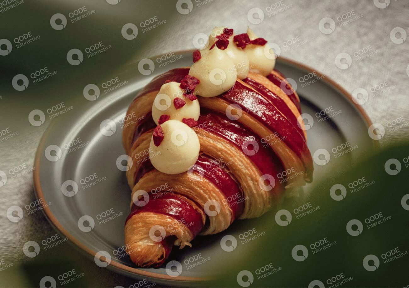 A croissant topped with cream and pomegranate seeds on a plate.