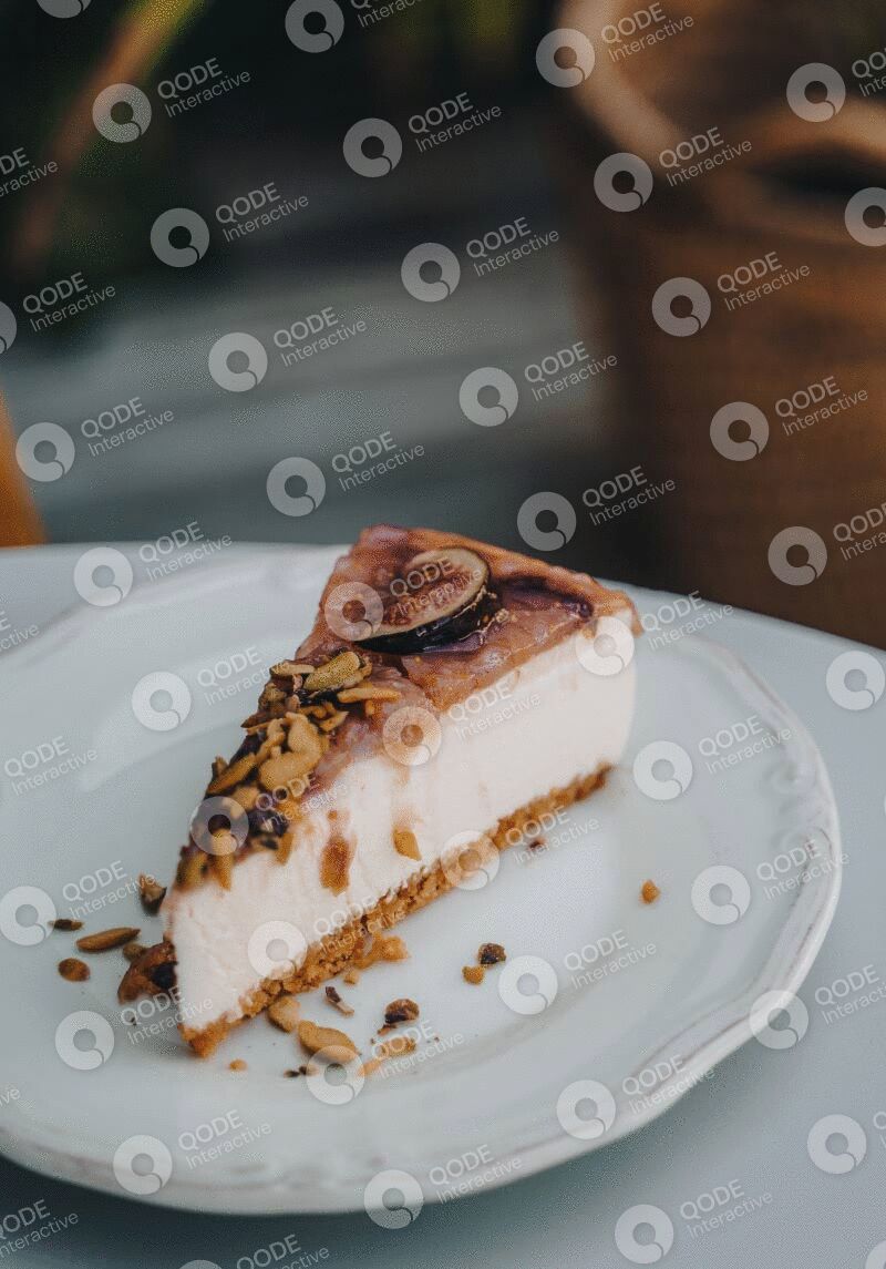 A slice of cheesecake topped with caramel and nuts on a white plate.