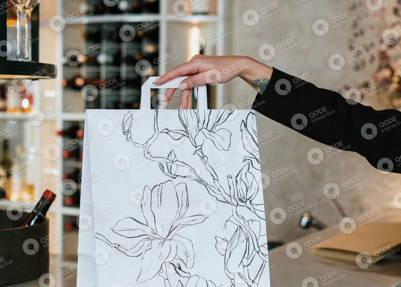 Hand holding a floral-patterned shopping bag.