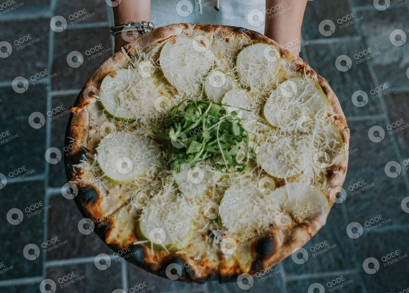 A pizza topped with onions, cheese, and greens.