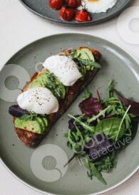 Avocado toast topped with poached egg and microgreens on a plate.