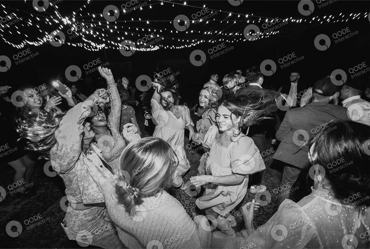 Black and white photo of people dancing joyfully at a lively party.
