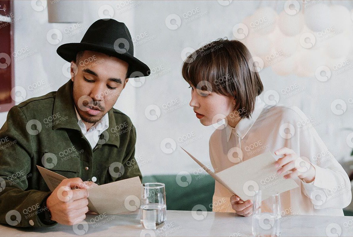 Two people discussing documents at a table with focused expressions.