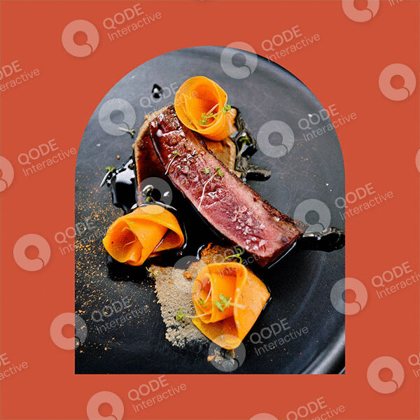 Gourmet beef steak with carrot ribbons and sauce on a dark plate.