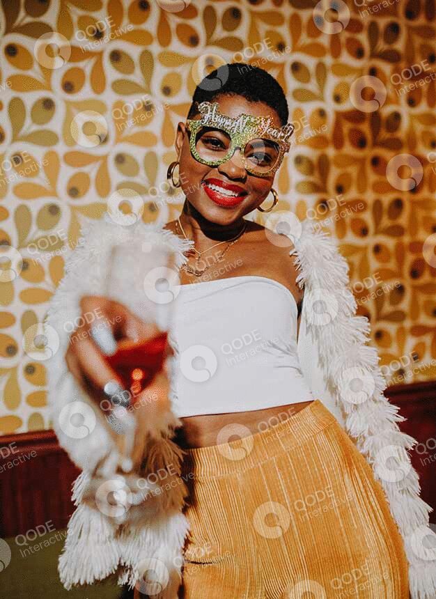 Smiling woman raising a glass in a lively setting.