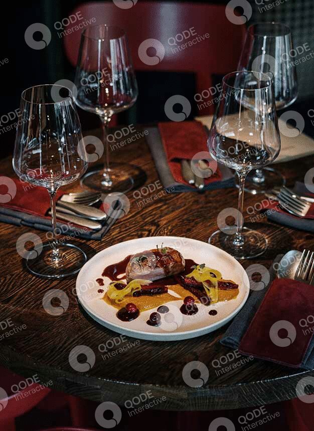 Elegant plated gourmet dish with wine glasses on a set dining table.