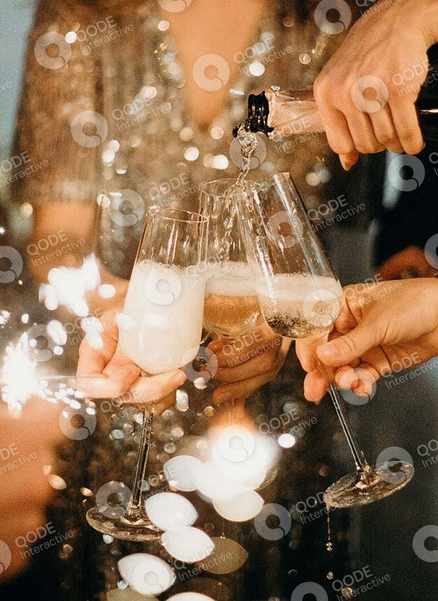 People clinking champagne glasses with sparklers in the background.