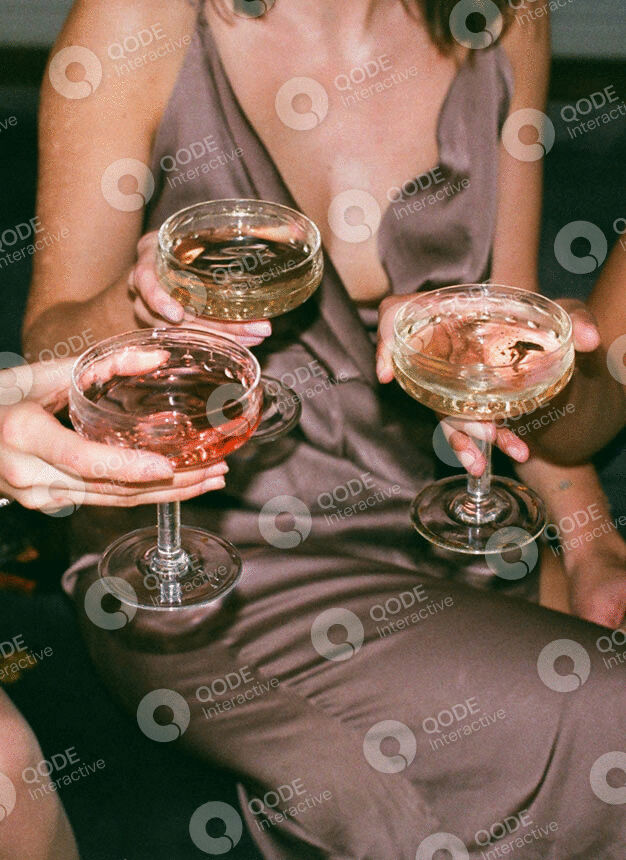 Three people holding elegant cocktail glasses filled with light-colored drinks.