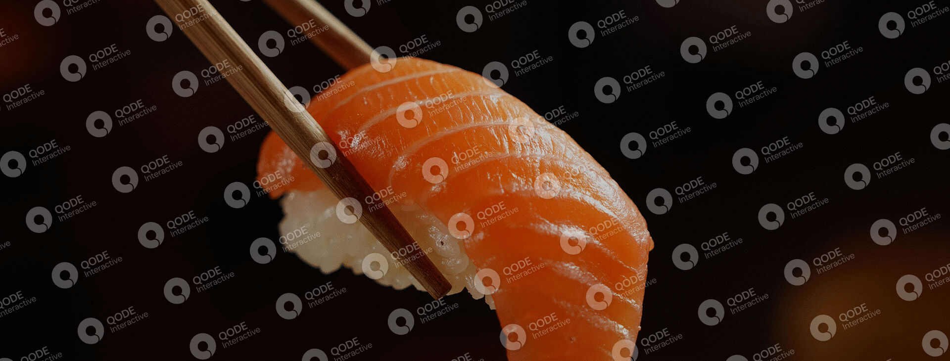 Close-up of salmon nigiri sushi with chopsticks.