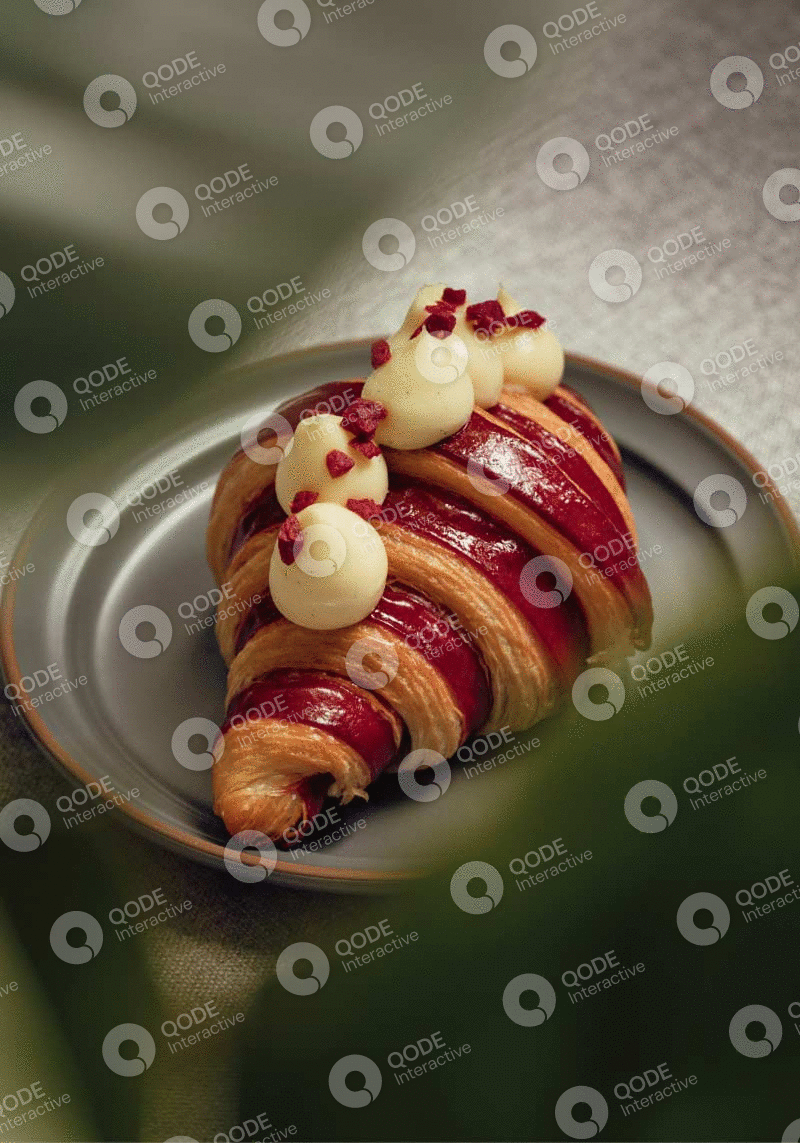 Gourmet croissant topped with cream and berries on a green plate.