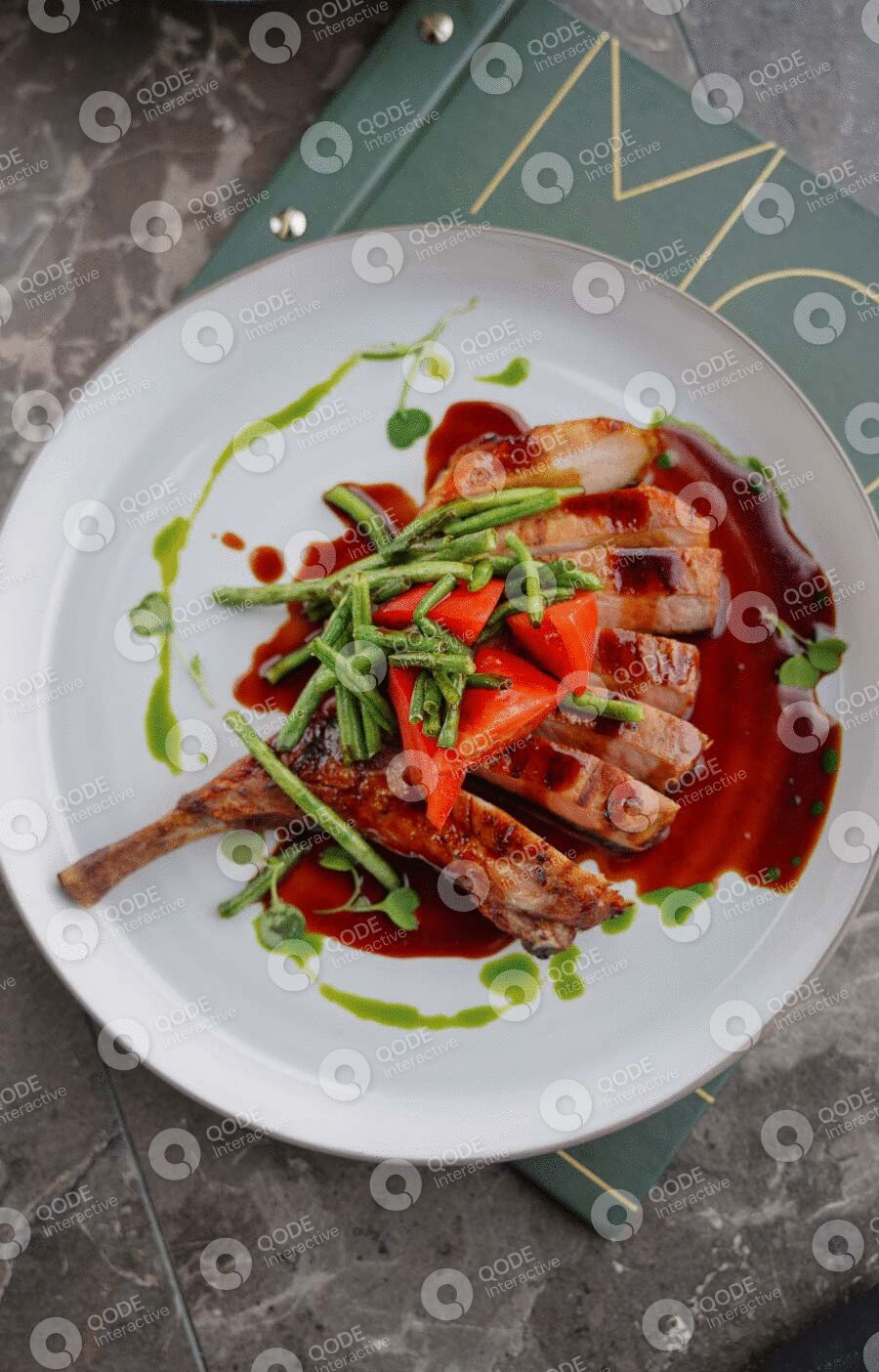 A gourmet dish with sliced meat, strawberries, and greens drizzled with sauce.