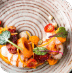 Elegant dessert with mango slices and berries on a textured glass plate.