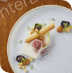 Elegant dessert with cream, fruit, and nuts on a white plate.