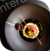 Elegant sushi piece served on a black plate with sauce.