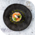 Elegant gourmet dish with colorful vegetables and sauce on a black plate.