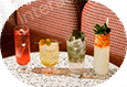 Four colorful cocktails lined up on a white table outdoors.