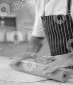 Person wearing striped apron working with dough on a table.