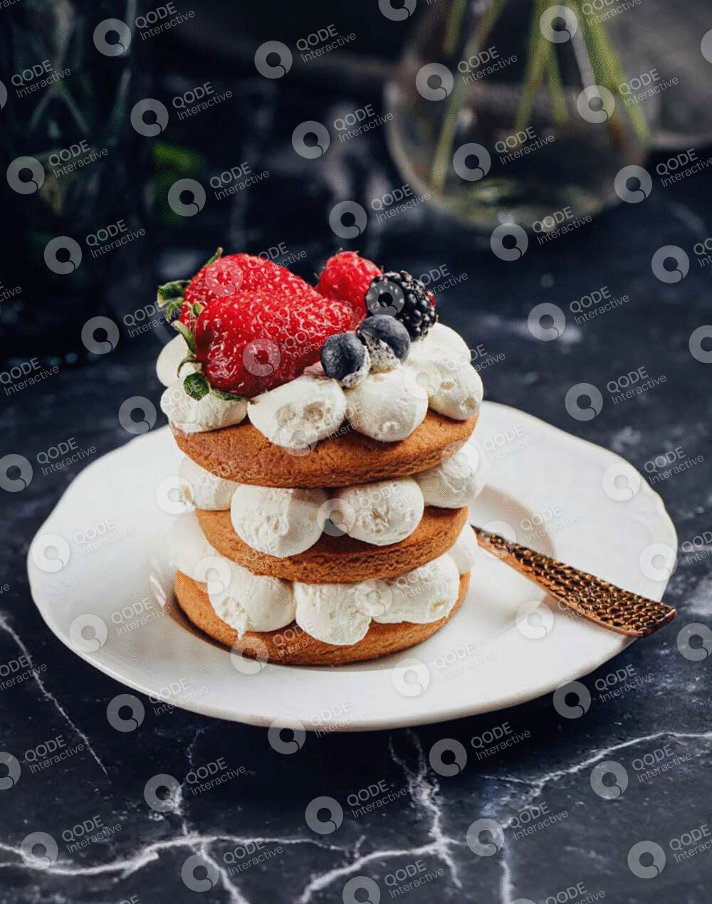 Layered dessert with cream, berries, and chocolate, topped with fresh raspberries and blueberries.