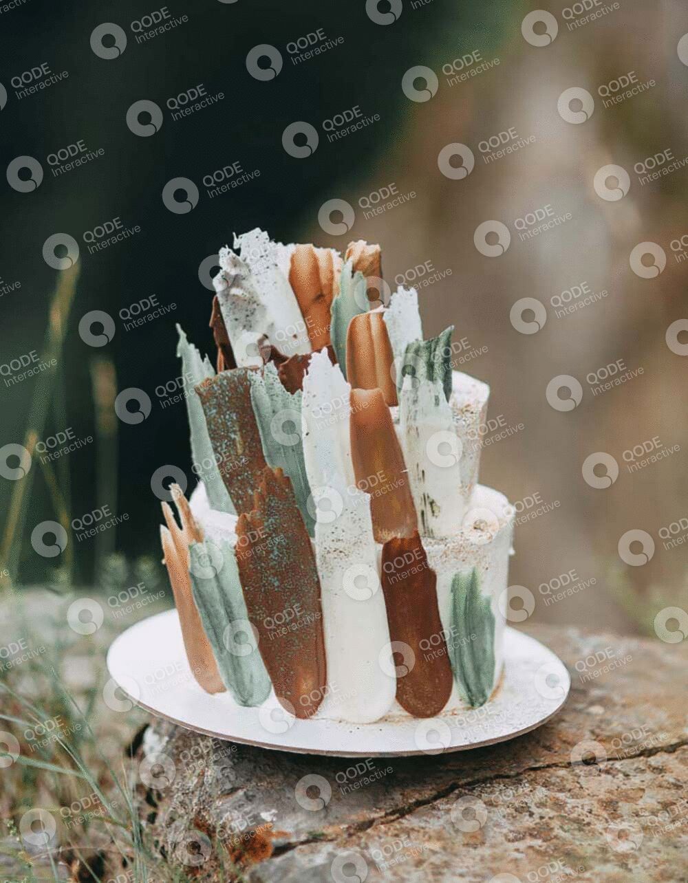 A unique white cake decorated with abstract caramel and green sugar art.