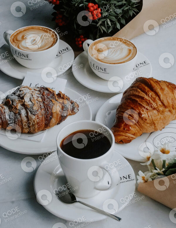 Three cups of coffee with croissants and pastries on a table.