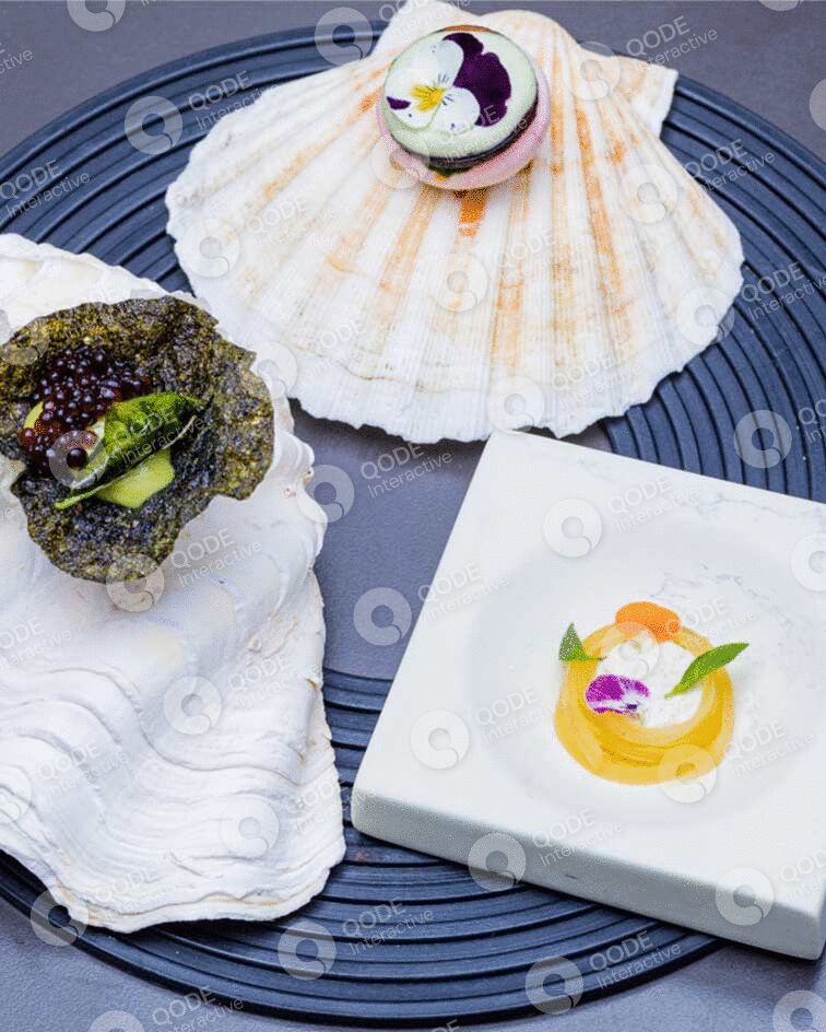 Elegant seafood dish served on seashells and a white plate.